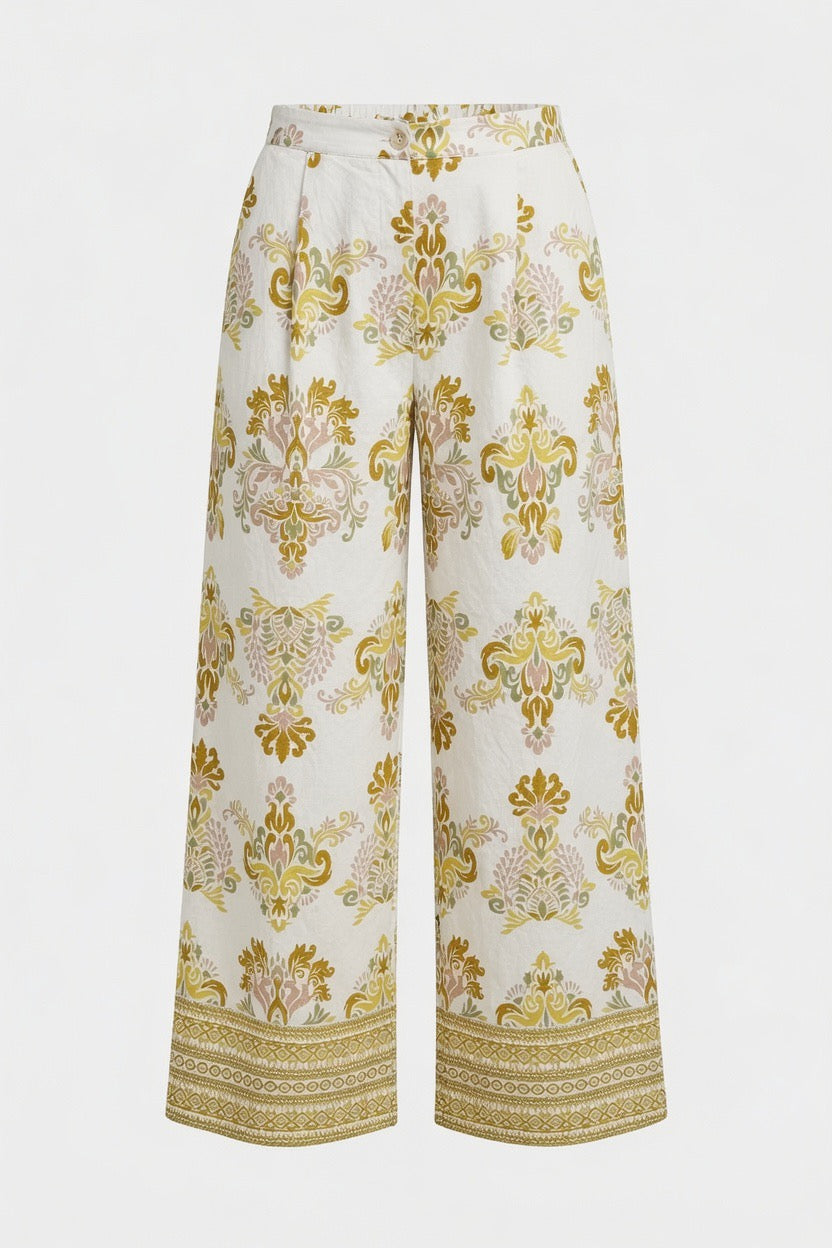 White wide-leg trousers with an ornate gold and pink damask pattern and a decorative gold border at the hem, shown against a plain white background.