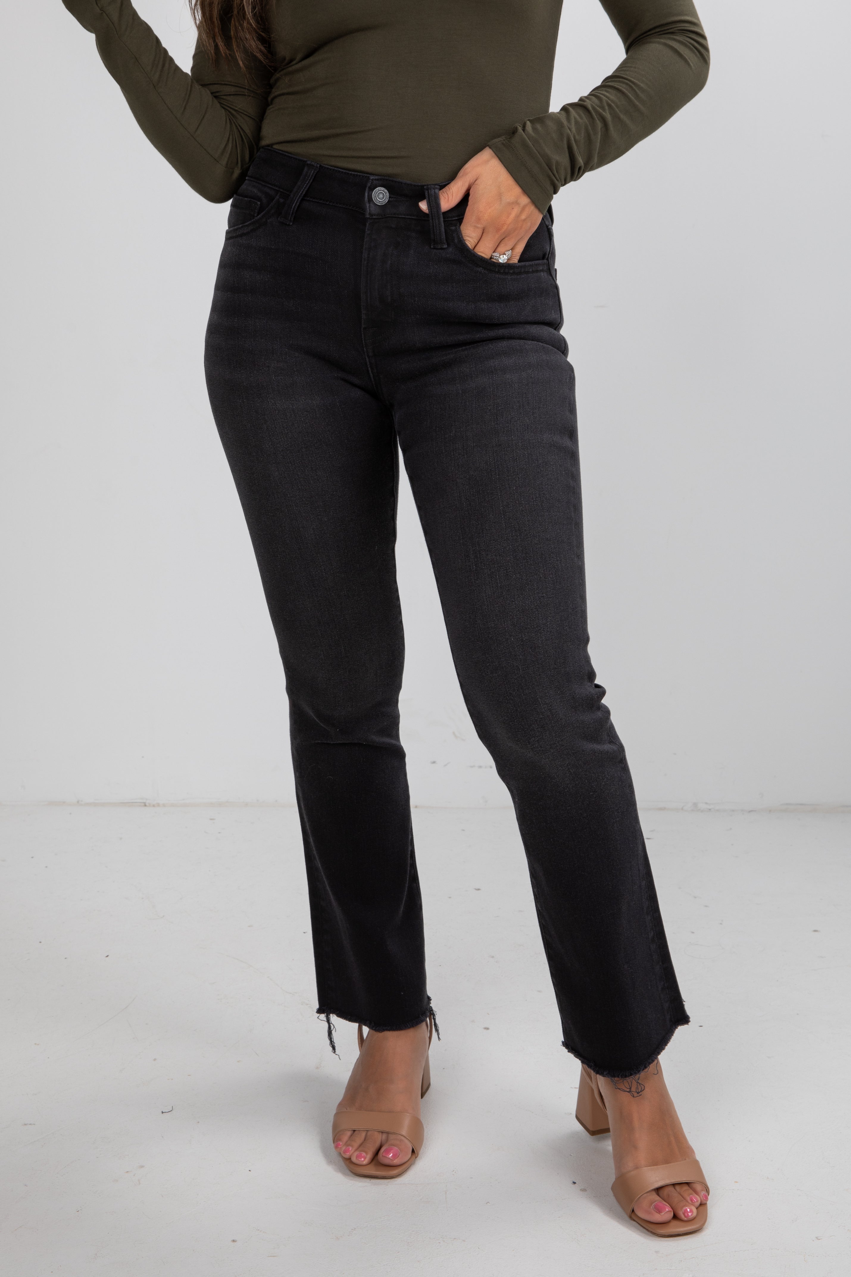 Person wearing black jeans and a green top on a white background