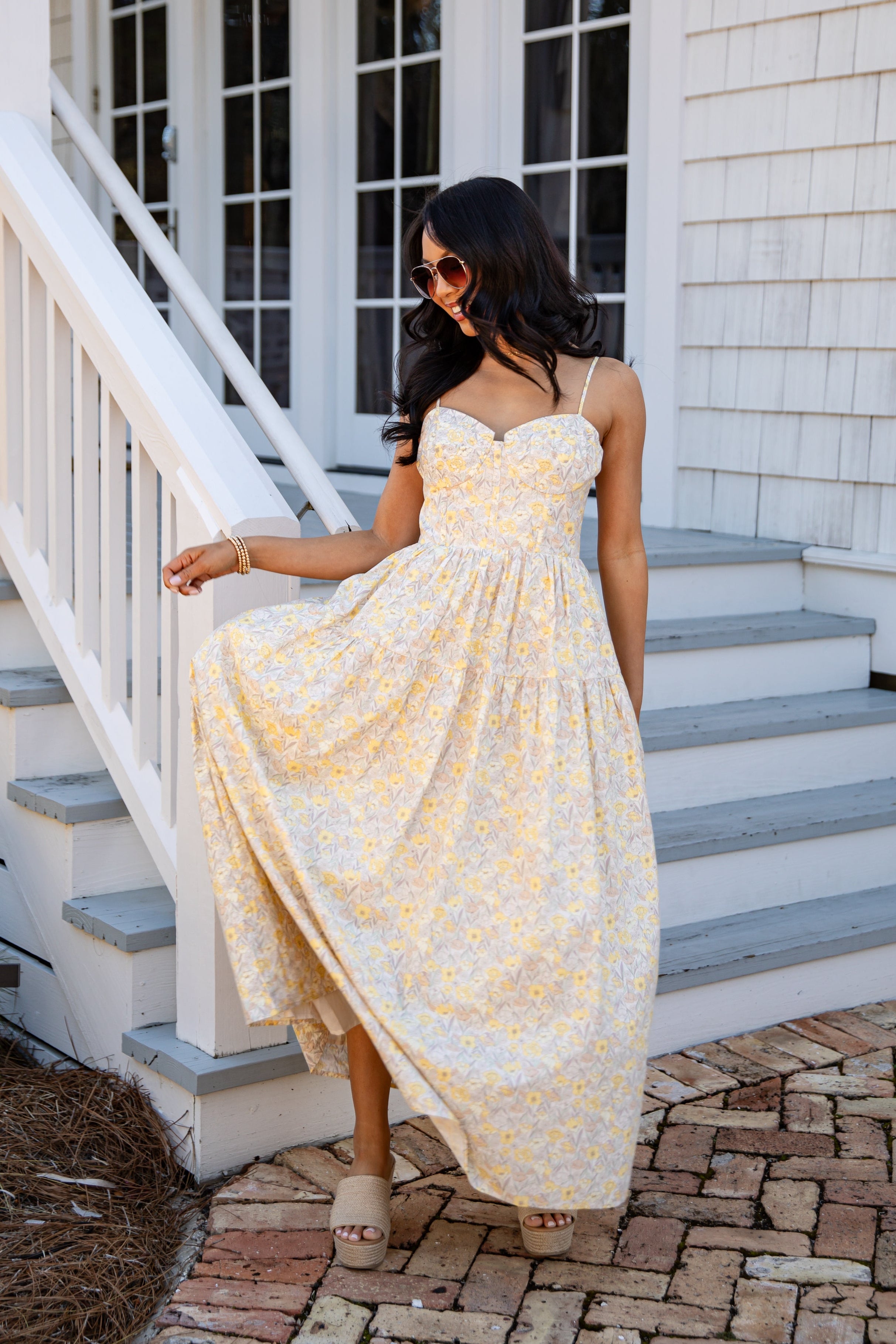 Woman in a yellow dress standing on a staircase outside a house