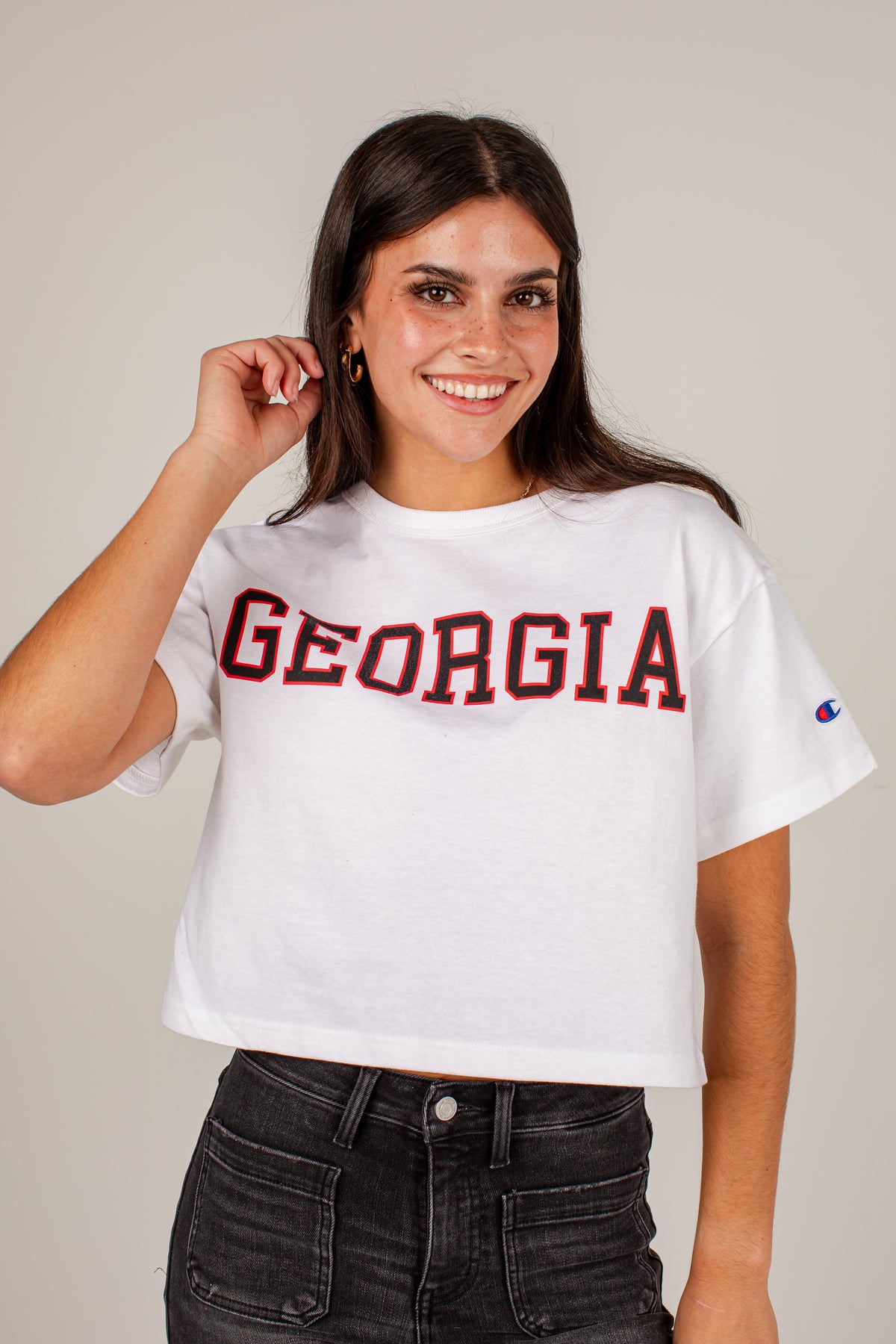 A woman wearing a white cropped t-shirt with &
