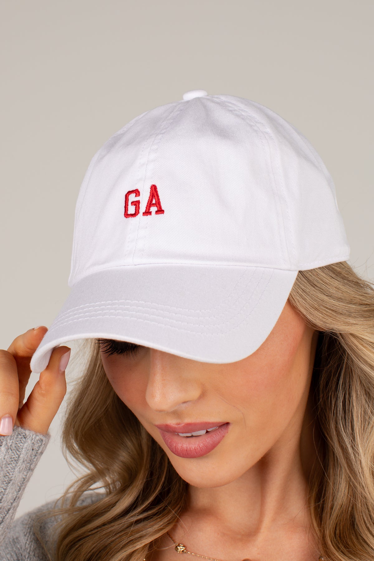 A woman wearing a white baseball cap with red embroidered letters &