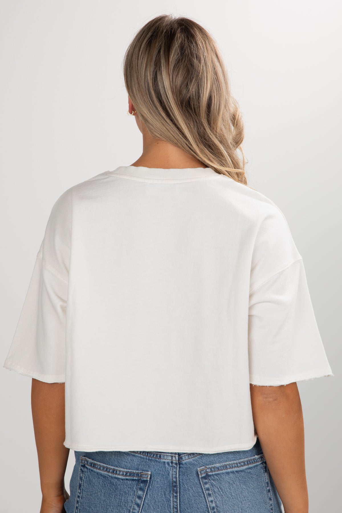 Person wearing a white t-shirt and blue jeans on a plain background