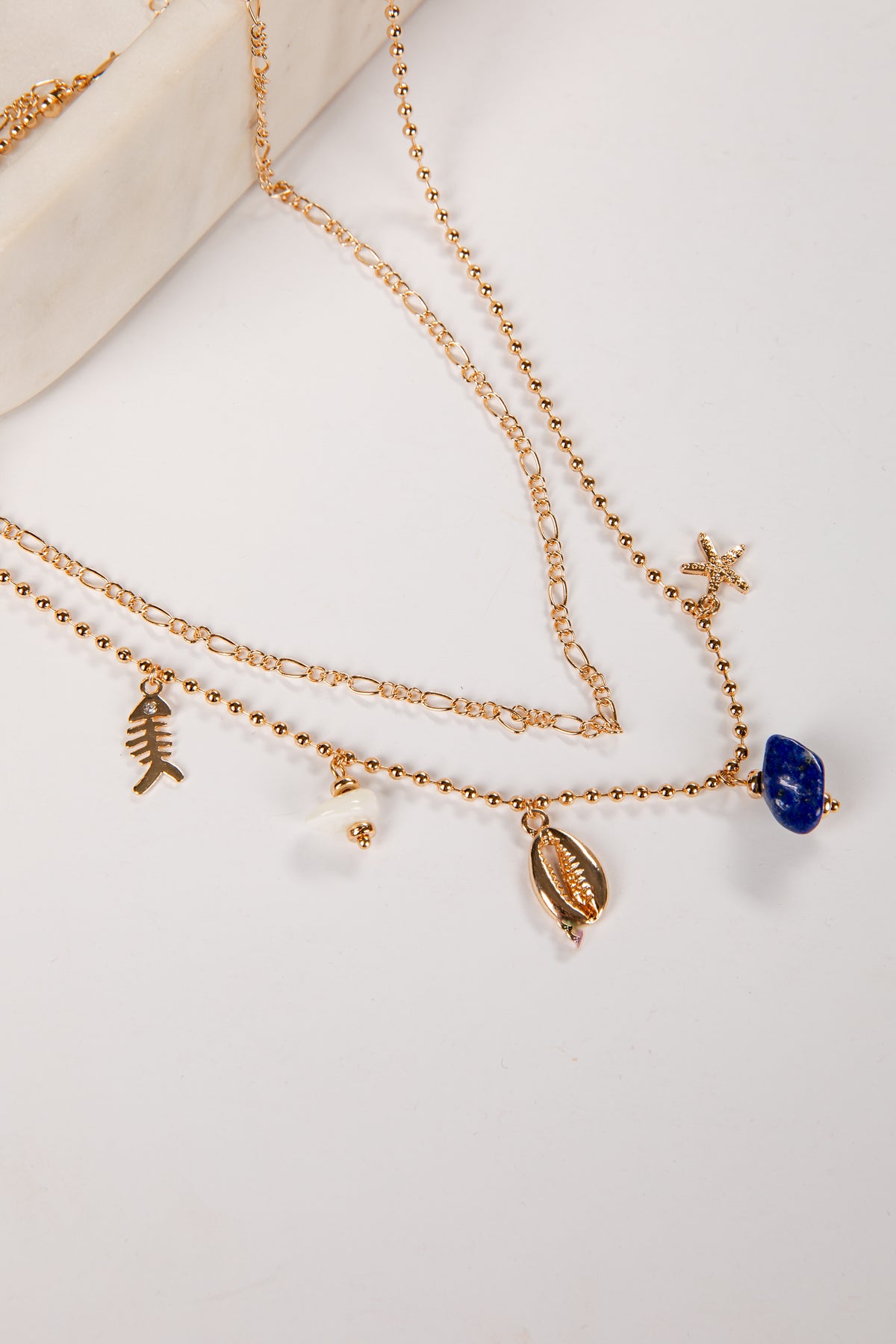 Gold necklaces with various charms on a white surface