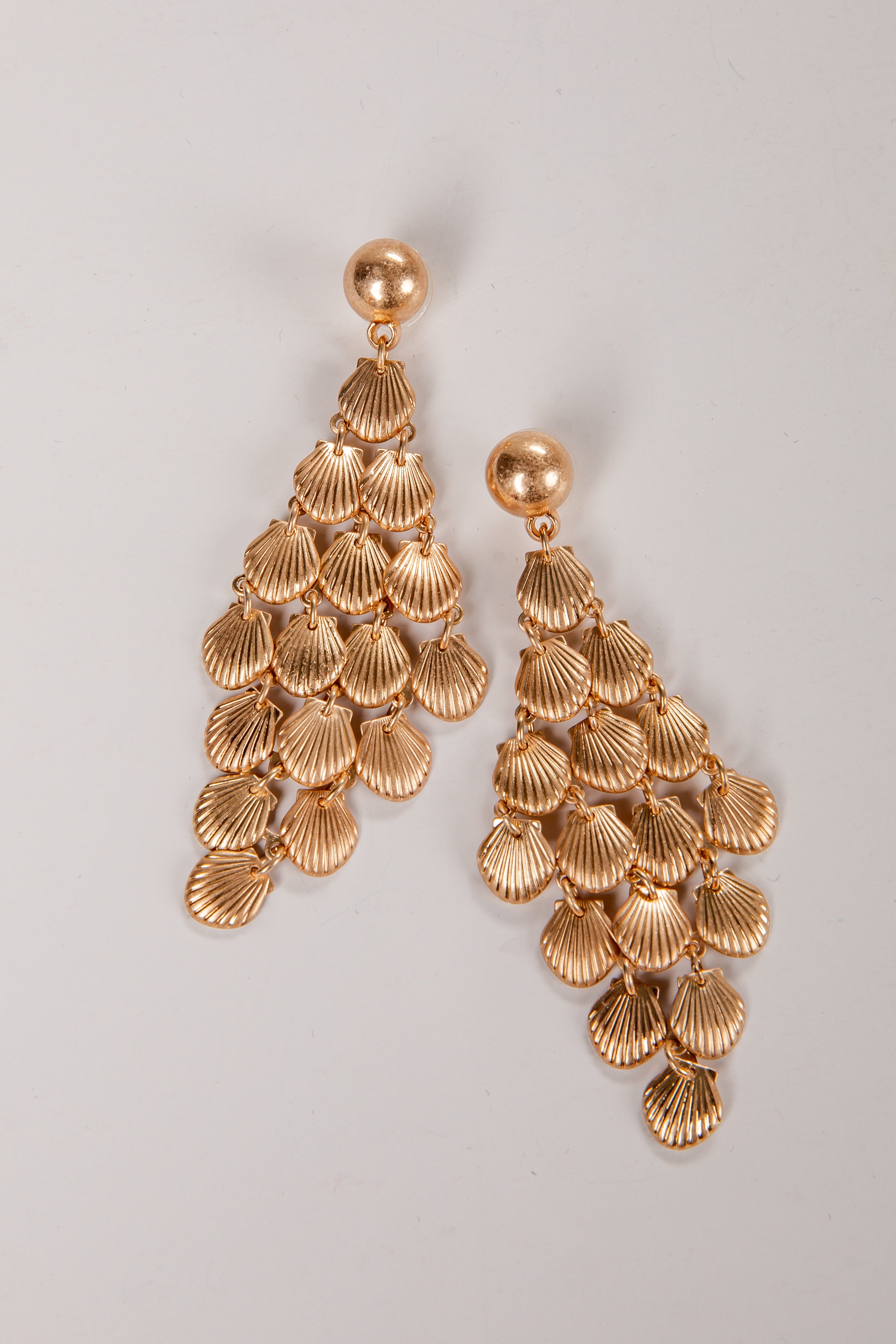 Gold shell-shaped earrings on a light gray background