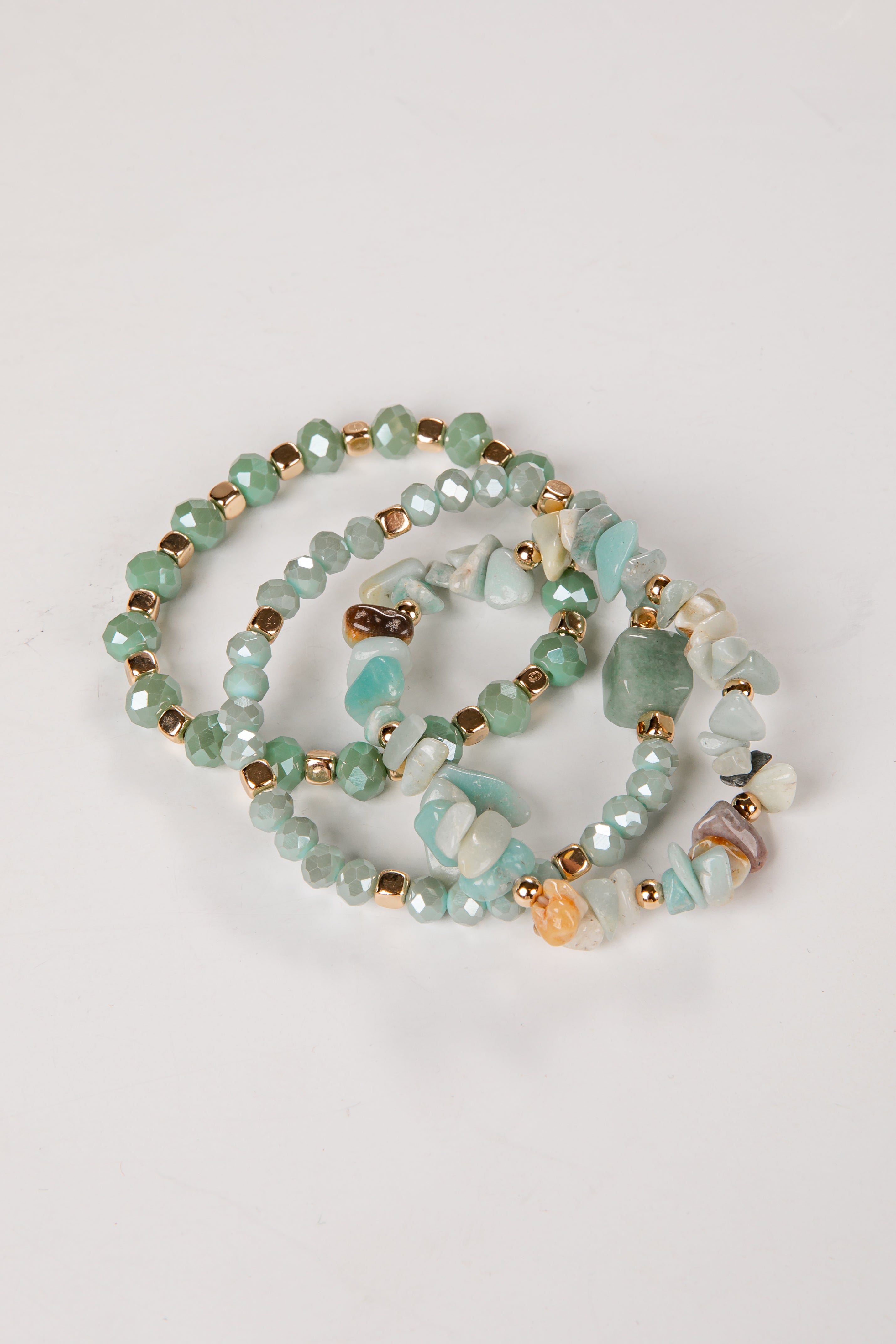 Beaded bracelets with green and gold beads on a light gray background