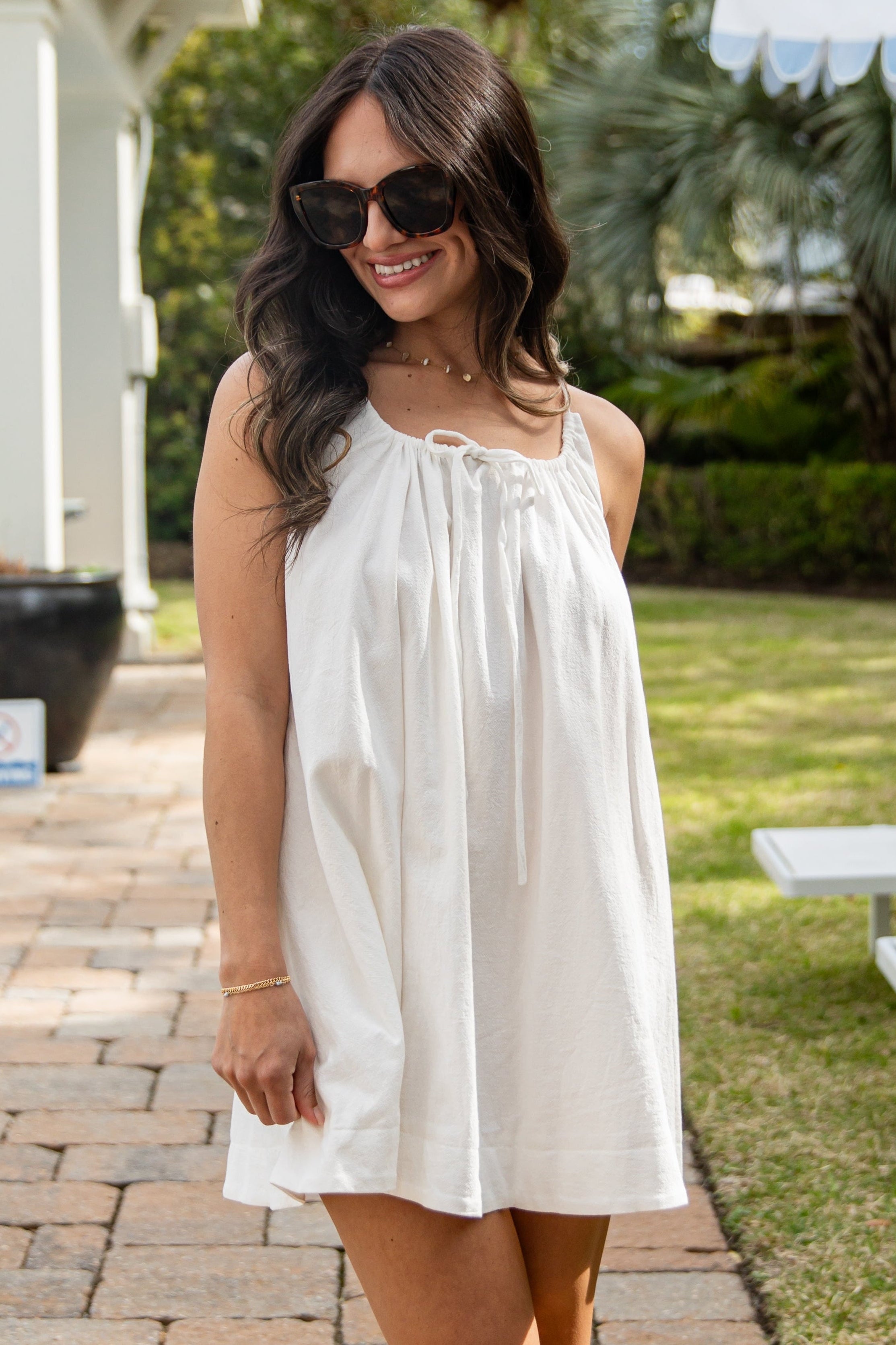 Woman in a white dress standing outdoors on a patio