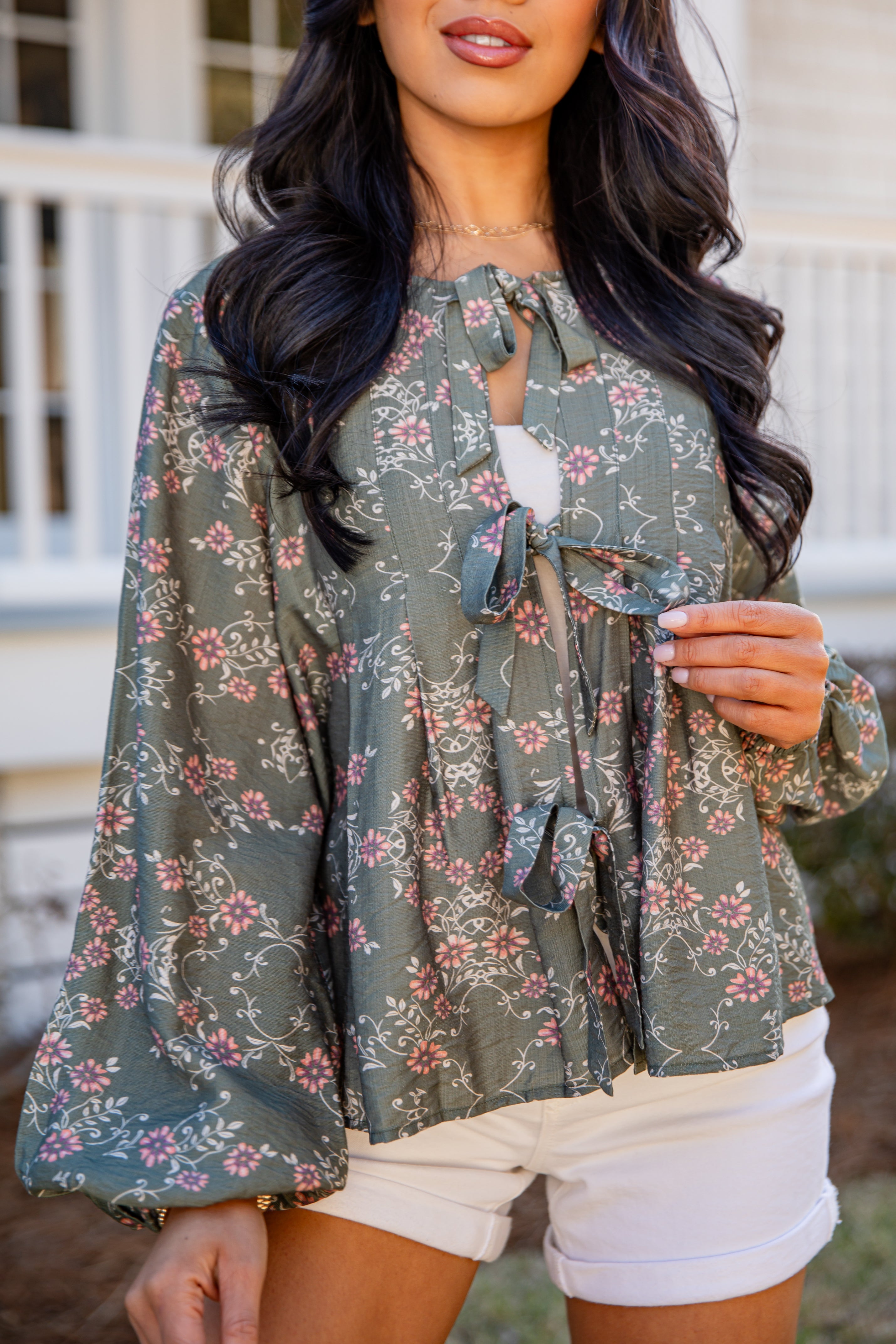 Woman wearing a green floral blouse with a blurred background