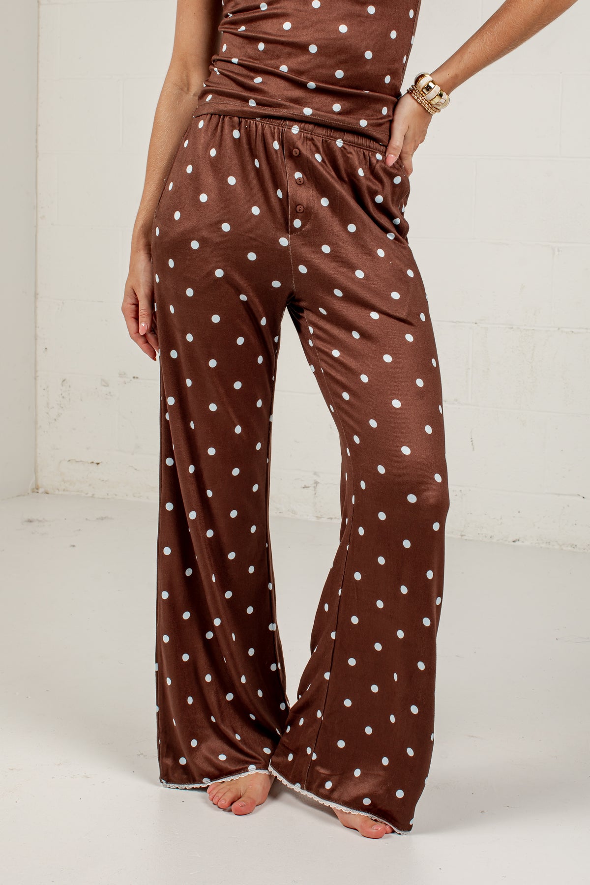 Brown wide-leg pants with a white polka dot pattern, shown on a model against a white studio background.