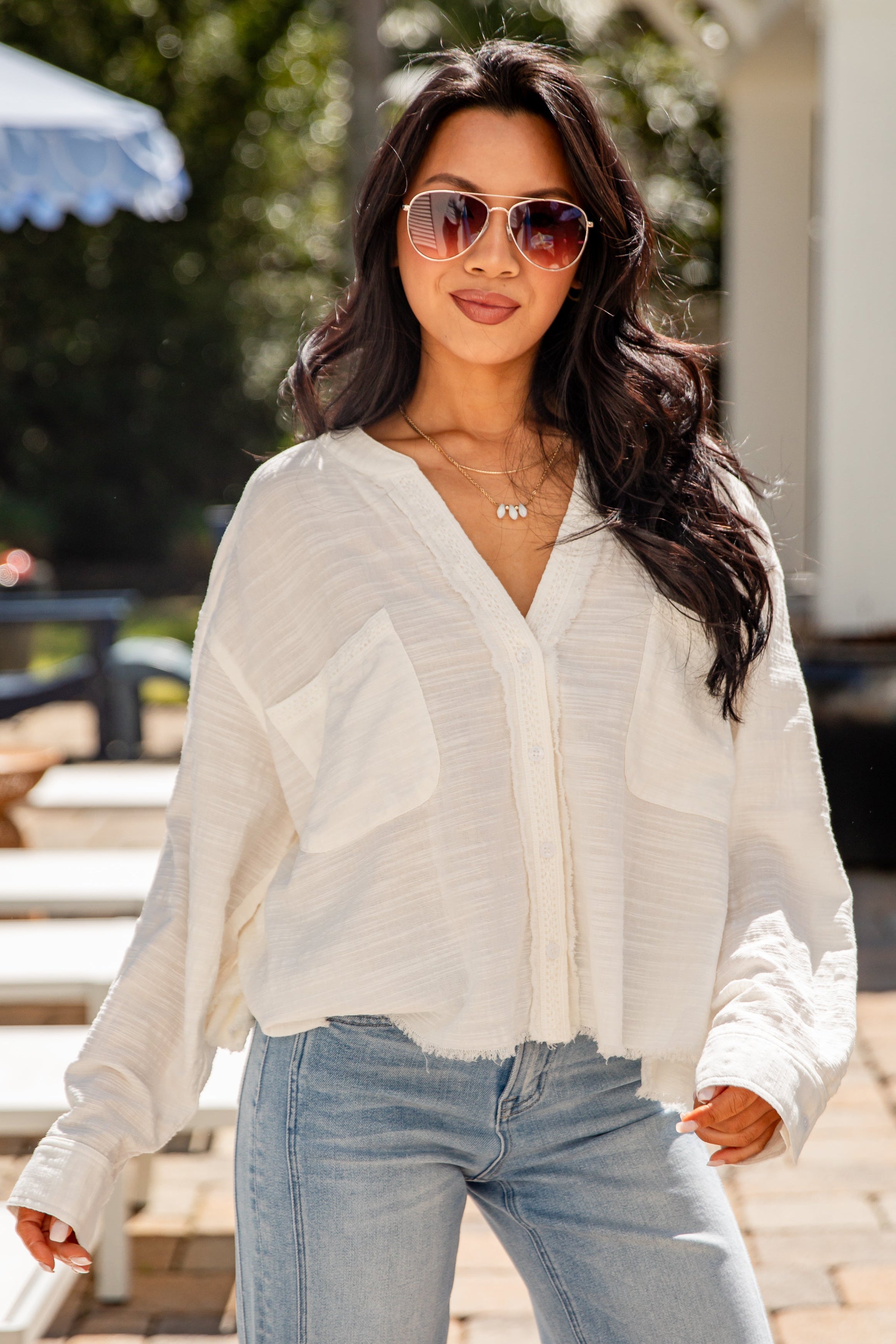 Woman wearing a white blouse and light blue jeans outdoors.