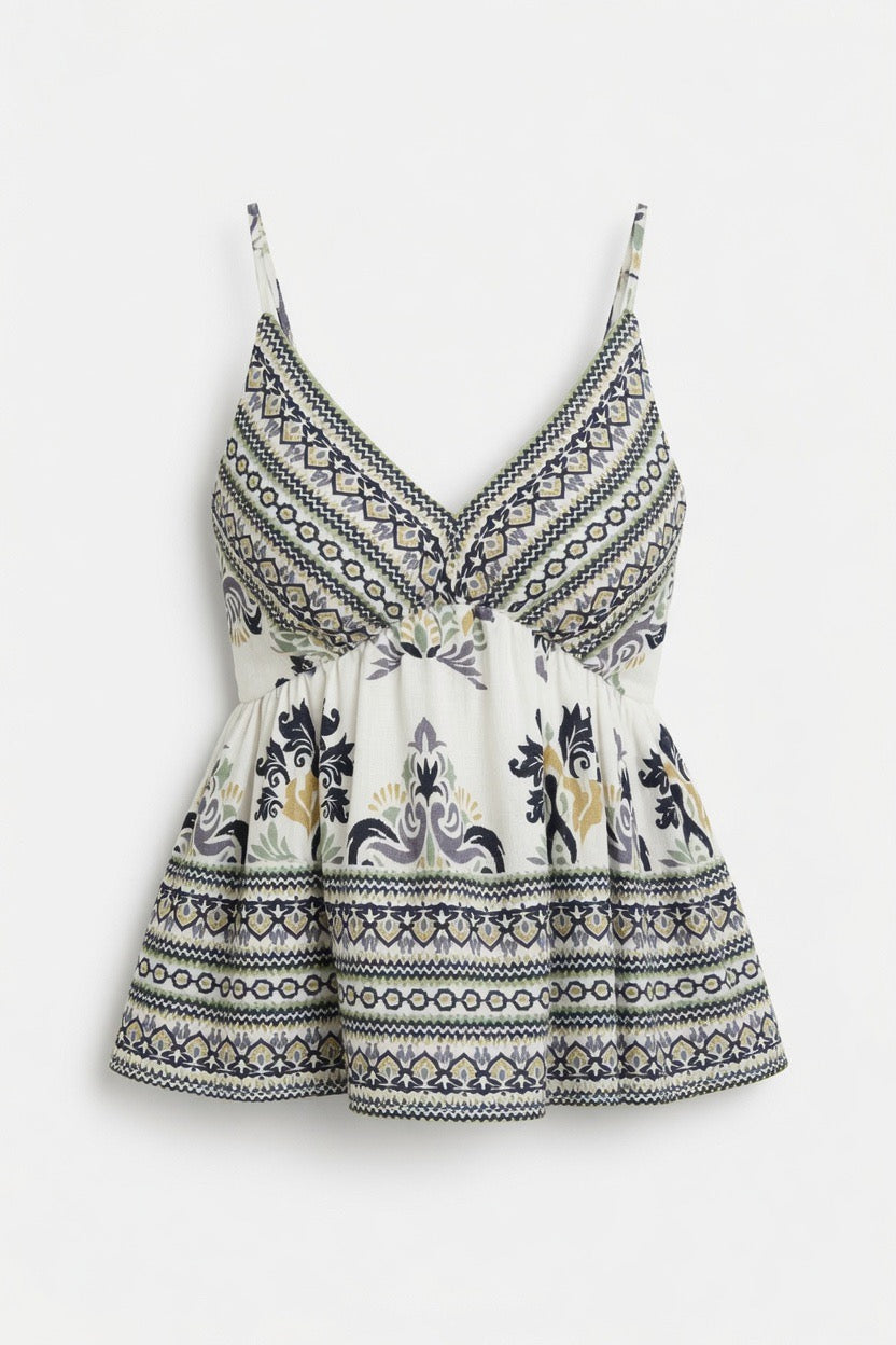 A sleeveless white camisole-style top with thin straps, a V-neckline, and a gathered peplum waist, featuring a navy and gray geometric border pattern and a central floral motif.