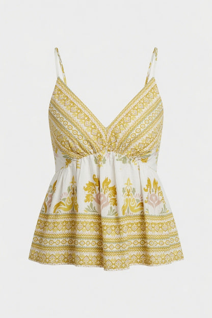 A sleeveless bohemian-style camisole top with thin straps, a V-neckline, and a gathered peplum waist. The fabric features a white base with yellow-gold geometric patterns and a central floral print in yellow, pink, and green, set against a plain light gray background.