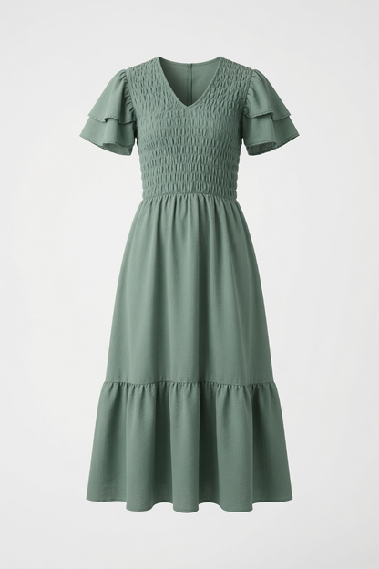 A woman wearing a sage green tiered maxi dress with ruffled short sleeves and smocked detailing