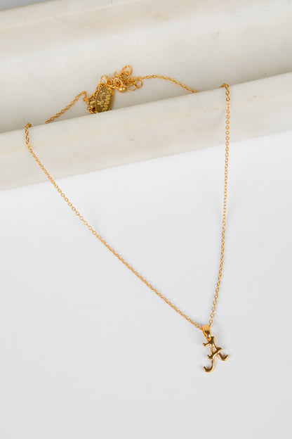 Gold necklace with a pendant on a white surface