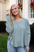 Woman wearing a light blue sweater and jeans standing in front of a house with Christmas decorations.