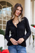 Woman in black top and blue jeans standing on a porch with Christmas decorations.