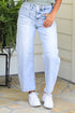 Person wearing a light green sleeveless top with bow details and light blue jeans, standing outdoors.