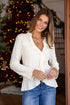 Woman wearing a white blouse and blue jeans standing in front of a decorated Christmas tree.