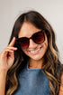 Woman wearing sunglasses and a denim top against a plain background