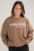 Person wearing a brown sweatshirt with &