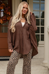 Woman in brown oversized shirt and leopard print pants standing on steps.