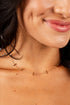 A close-up of a model wearing a delicate rose gold necklace with small, spaced-out T-shaped links.