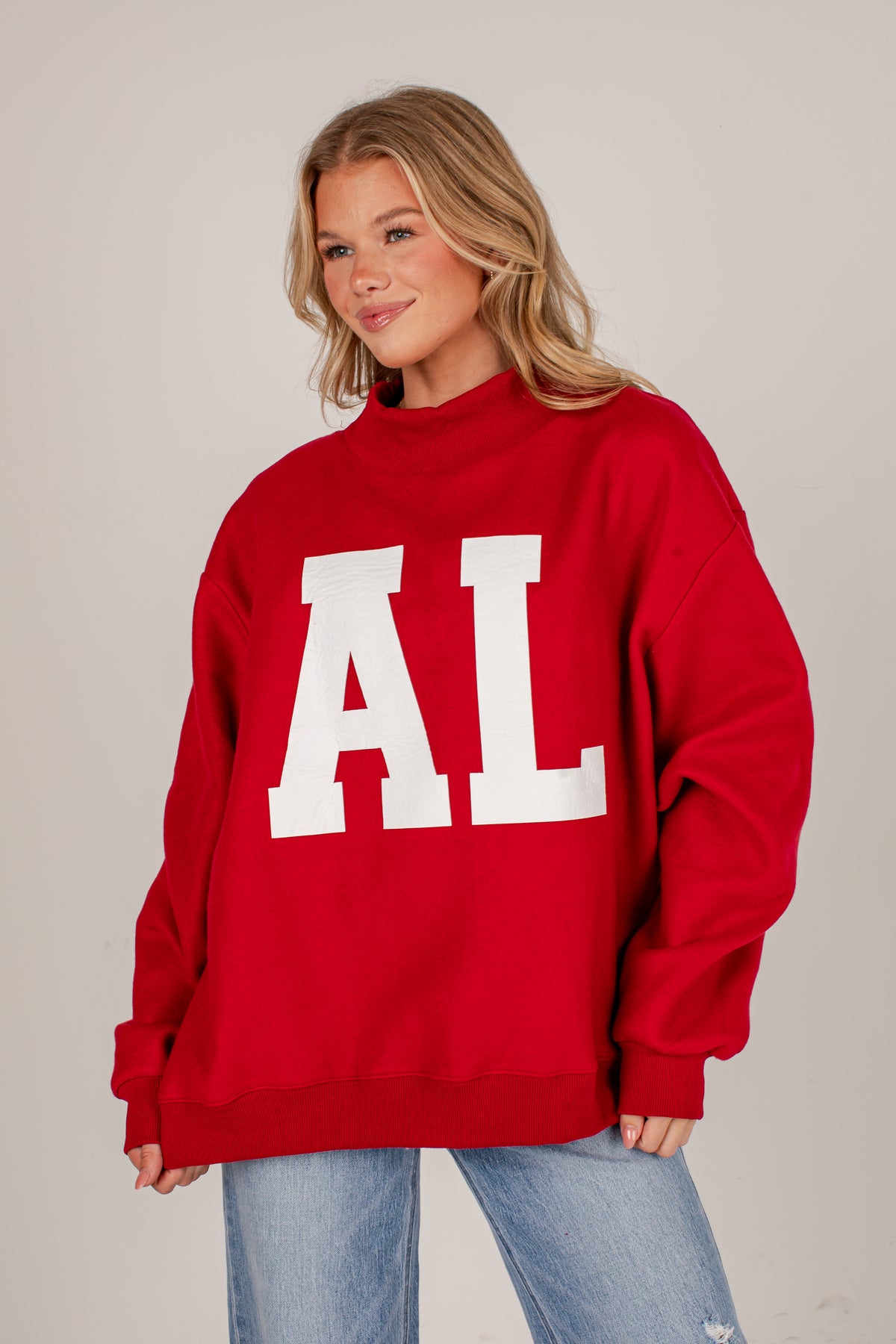 A woman wearing an oversized red sweatshirt with large white block letters &