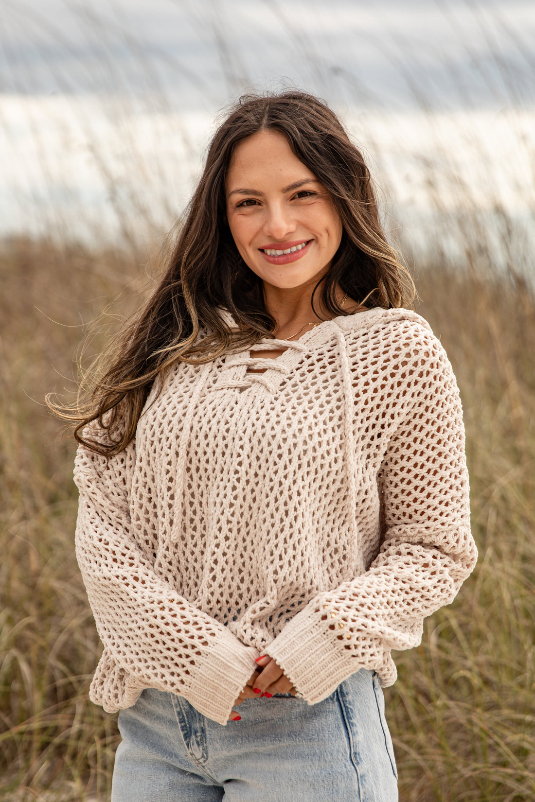 Woman wearing a beige knitted sweater in an outdoor setting