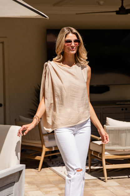 Woman in beige top and white pants standing on a patio