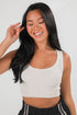 Woman wearing a white tank top against a plain background