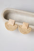 Pair of beige earrings on a white tray with a light gray background