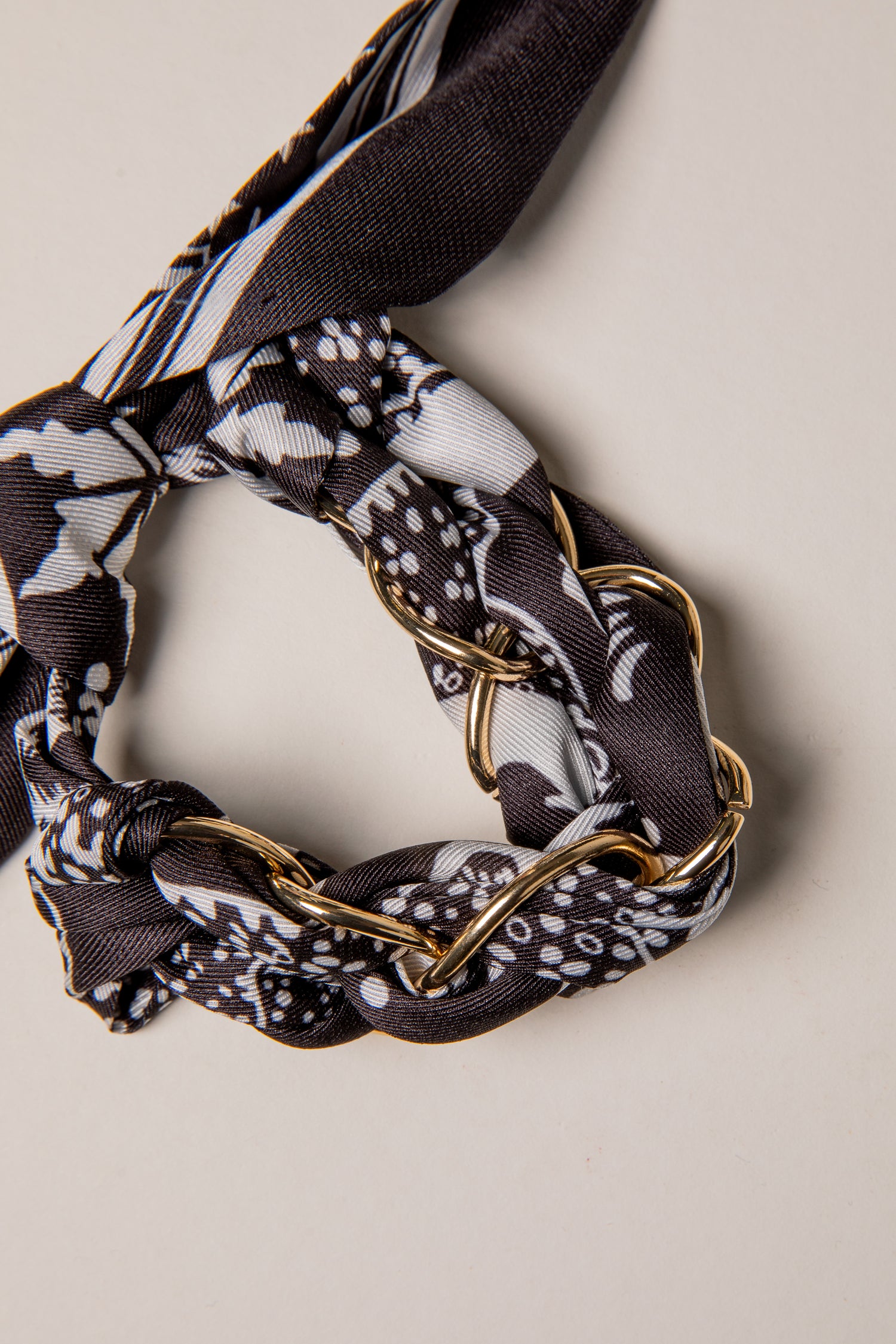 Scarf with gold chain detail on a neutral background