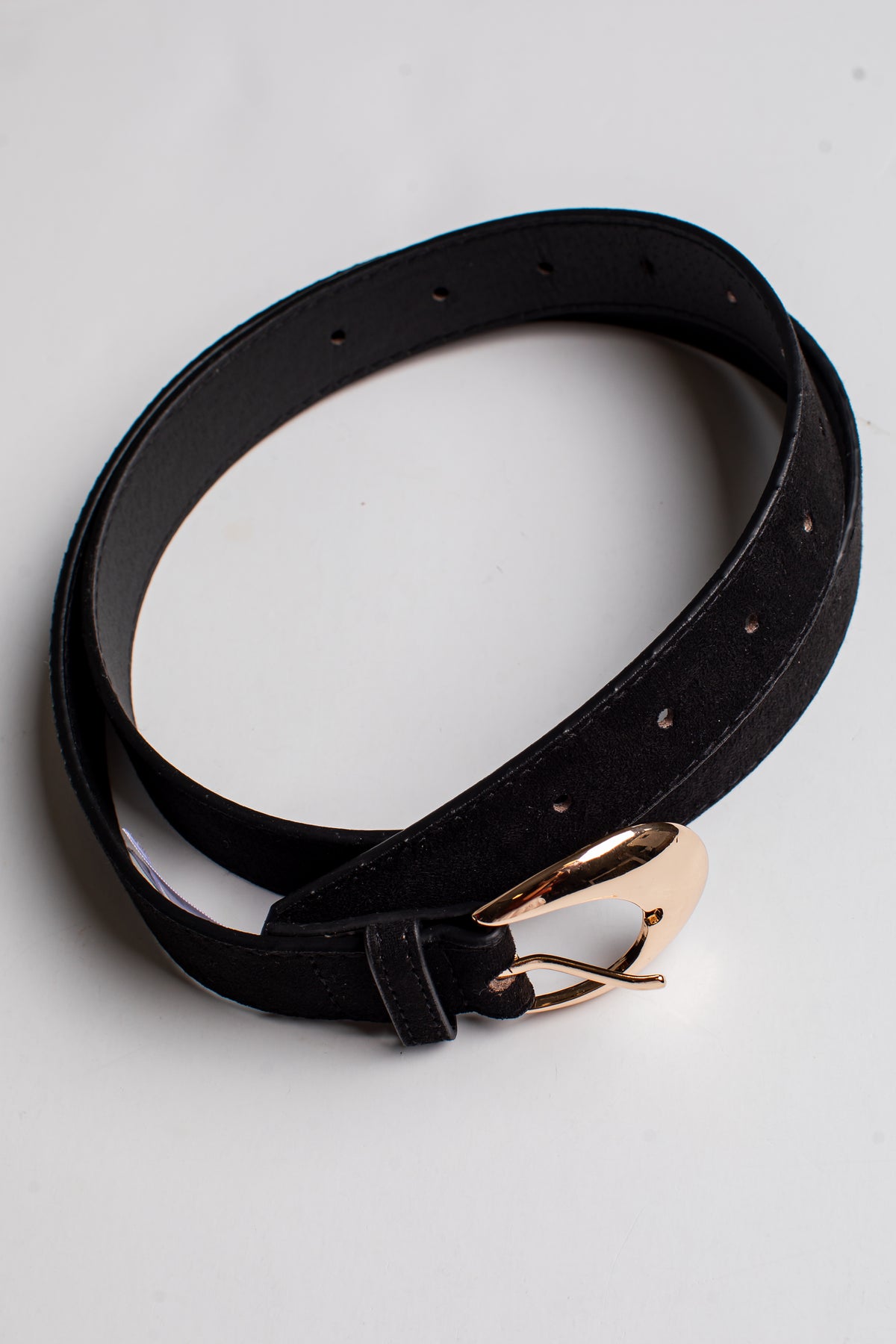 A black leather belt with a polished rose gold buckle, neatly coiled on a light gray background.