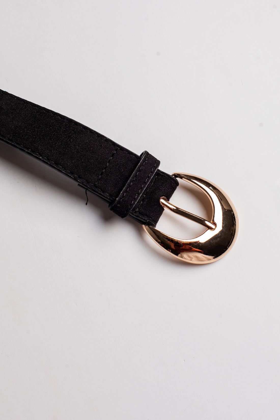 A close-up of a black belt strap with a polished rose gold buckle, shown on a clean white background.