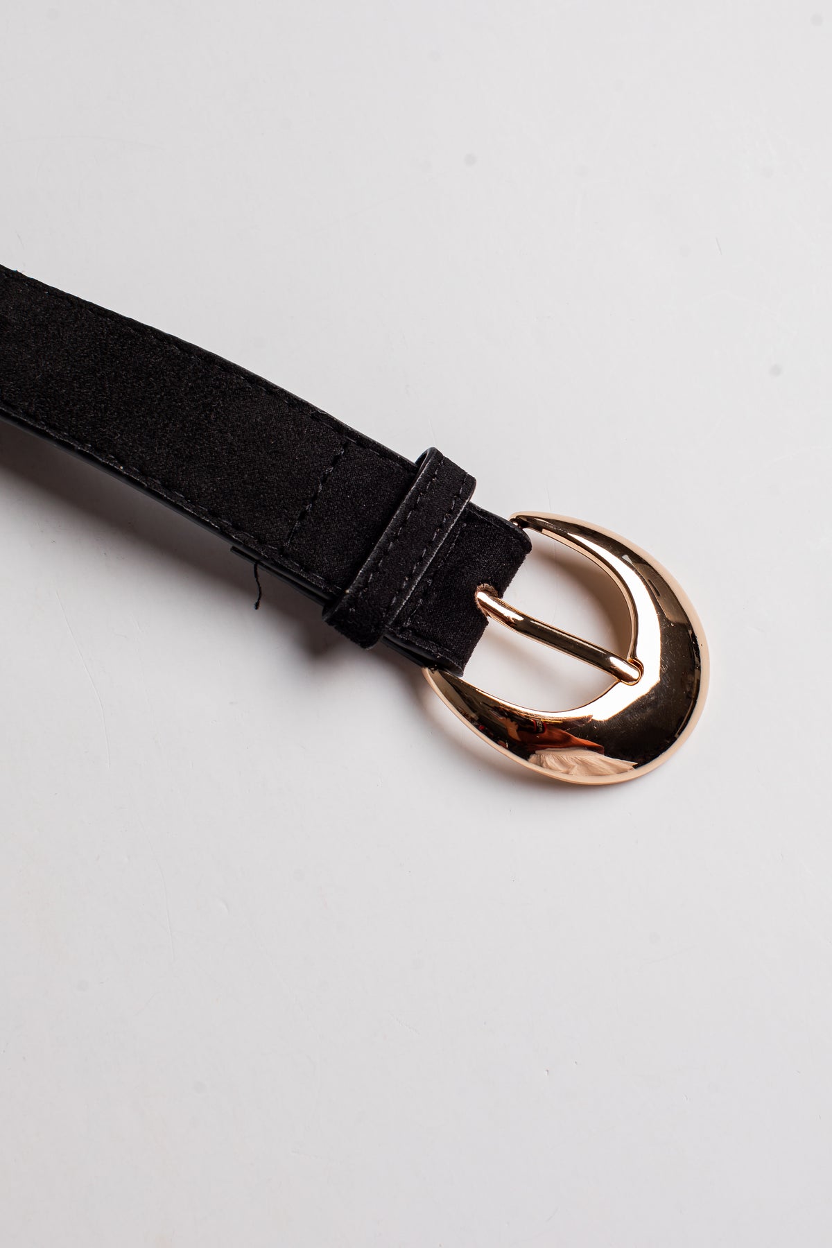 A close-up of a black belt strap with a polished rose gold buckle, shown on a clean white background.