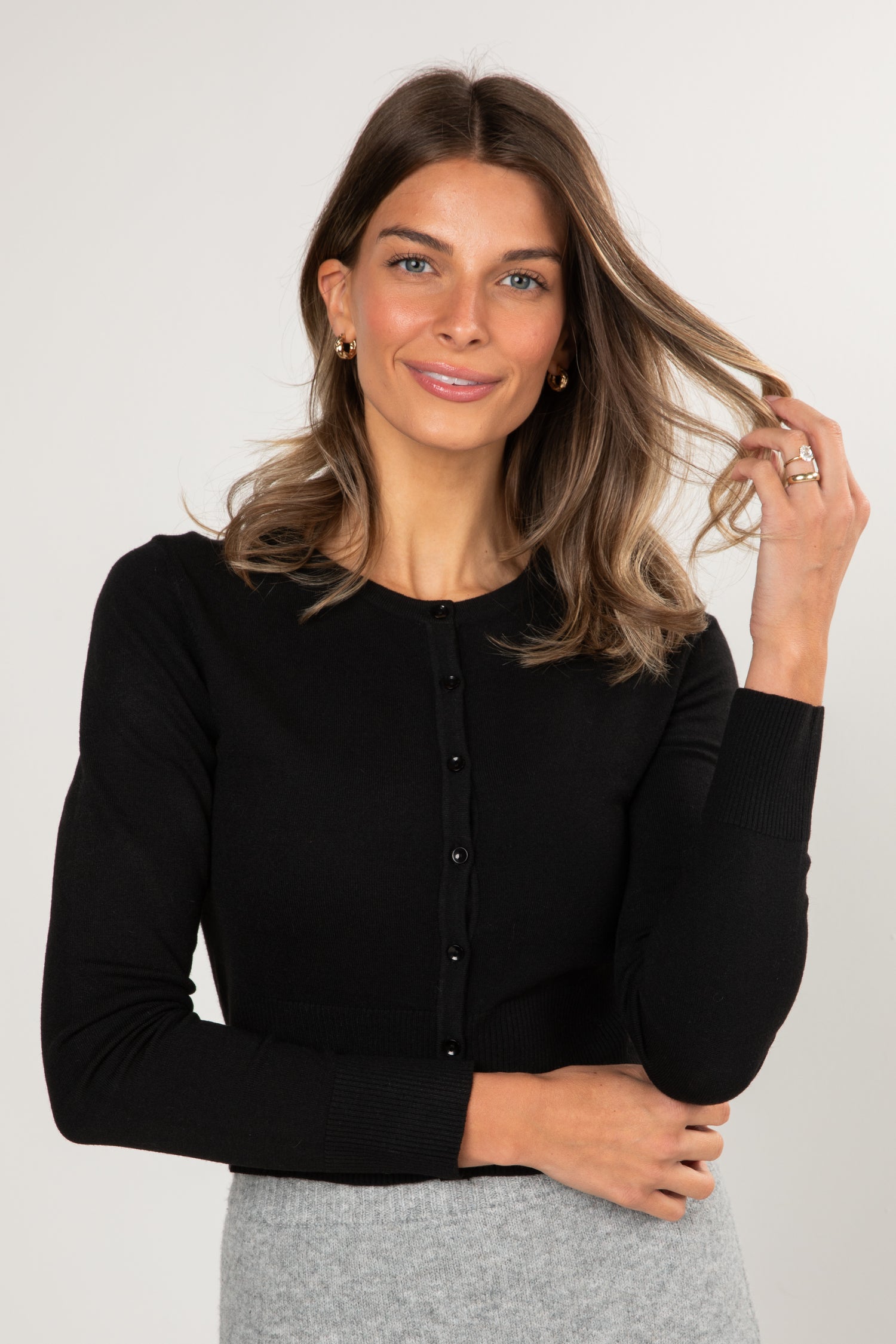 Woman wearing a black long-sleeve top against a plain background