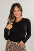 Woman wearing a black long-sleeve top and leopard print skirt on a plain background