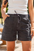 Person wearing a white top and black shorts with a blurred outdoor background
