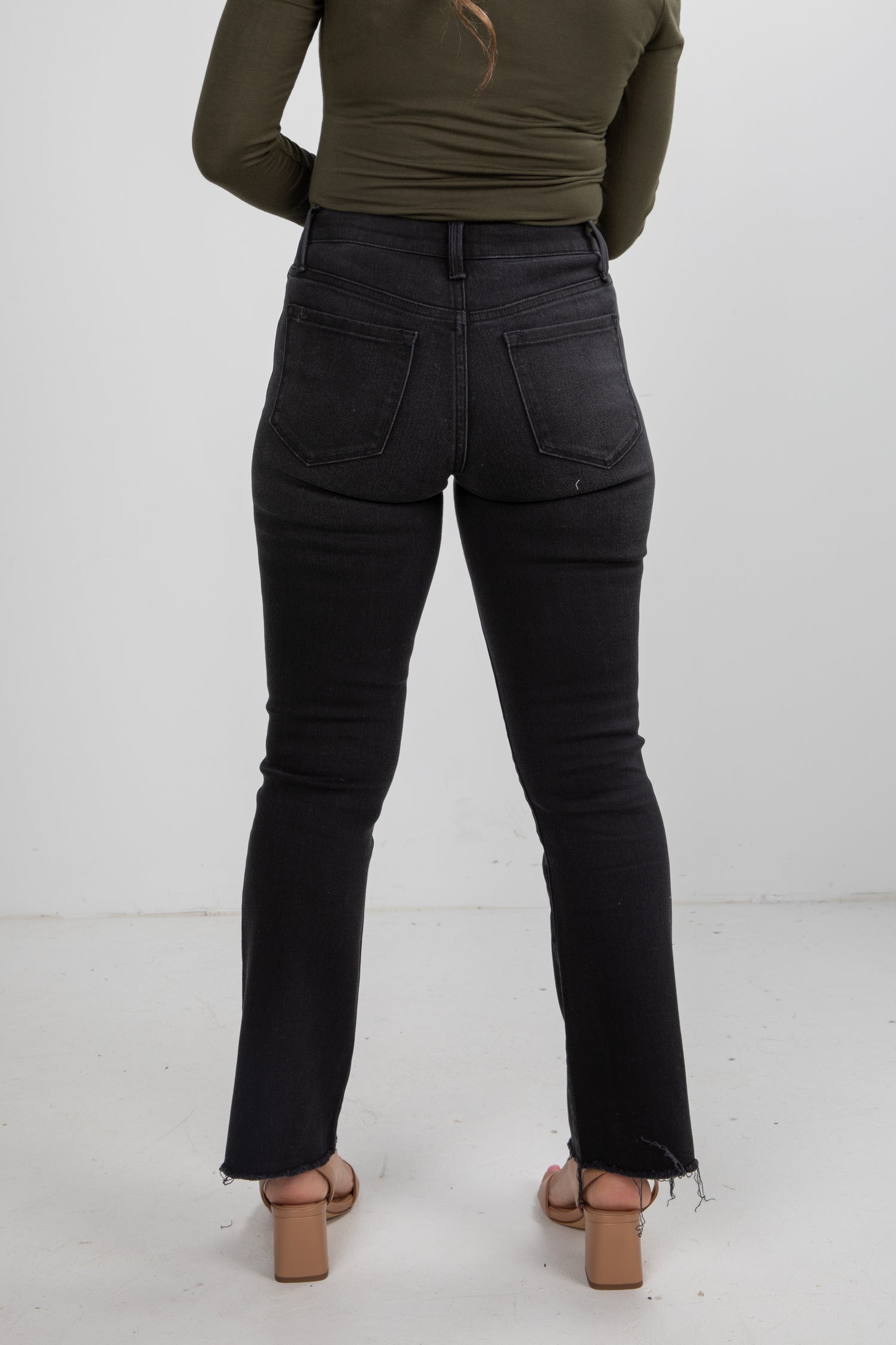Person wearing black jeans and a green top on a white background