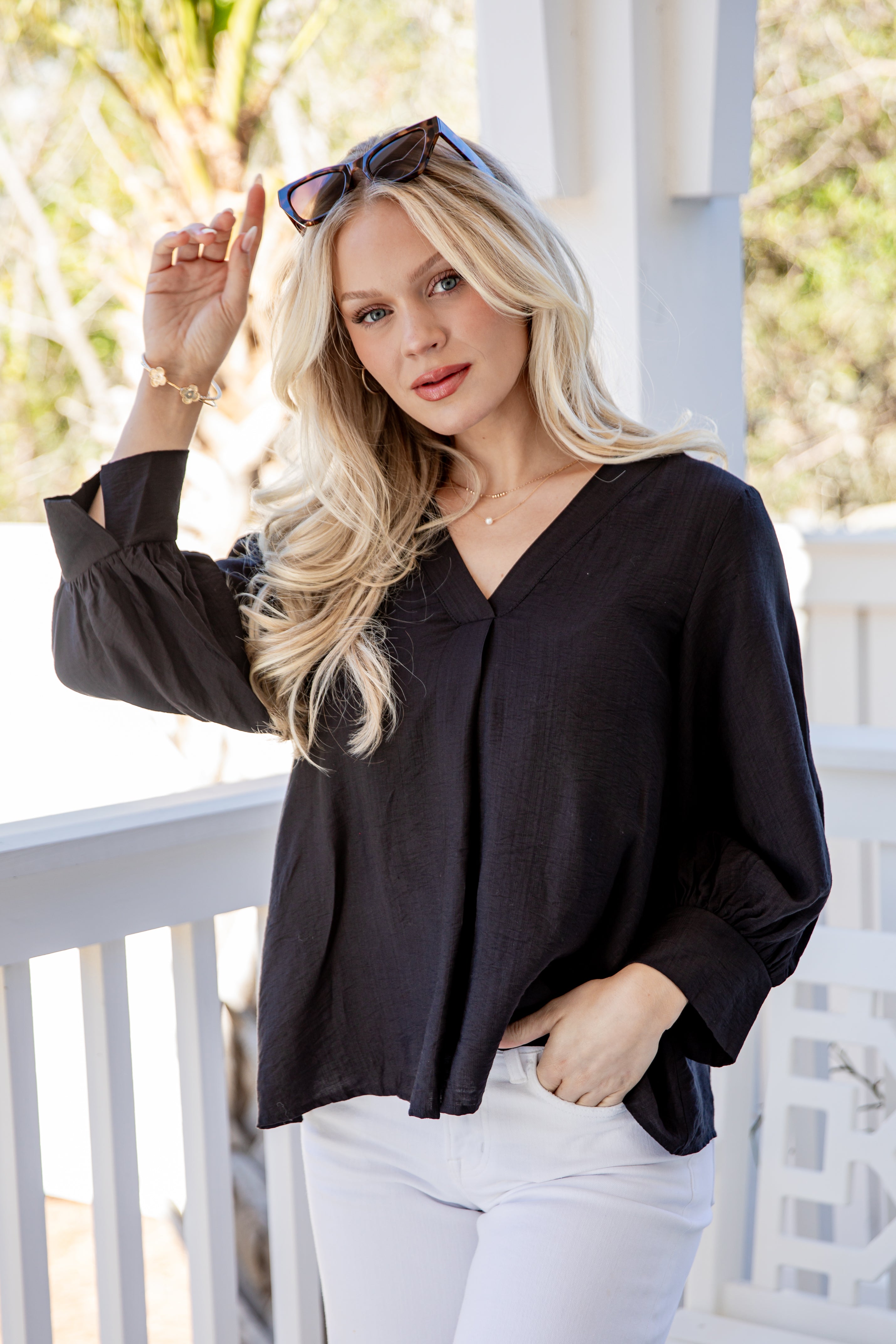 Woman wearing a black blouse and white pants on a balcony