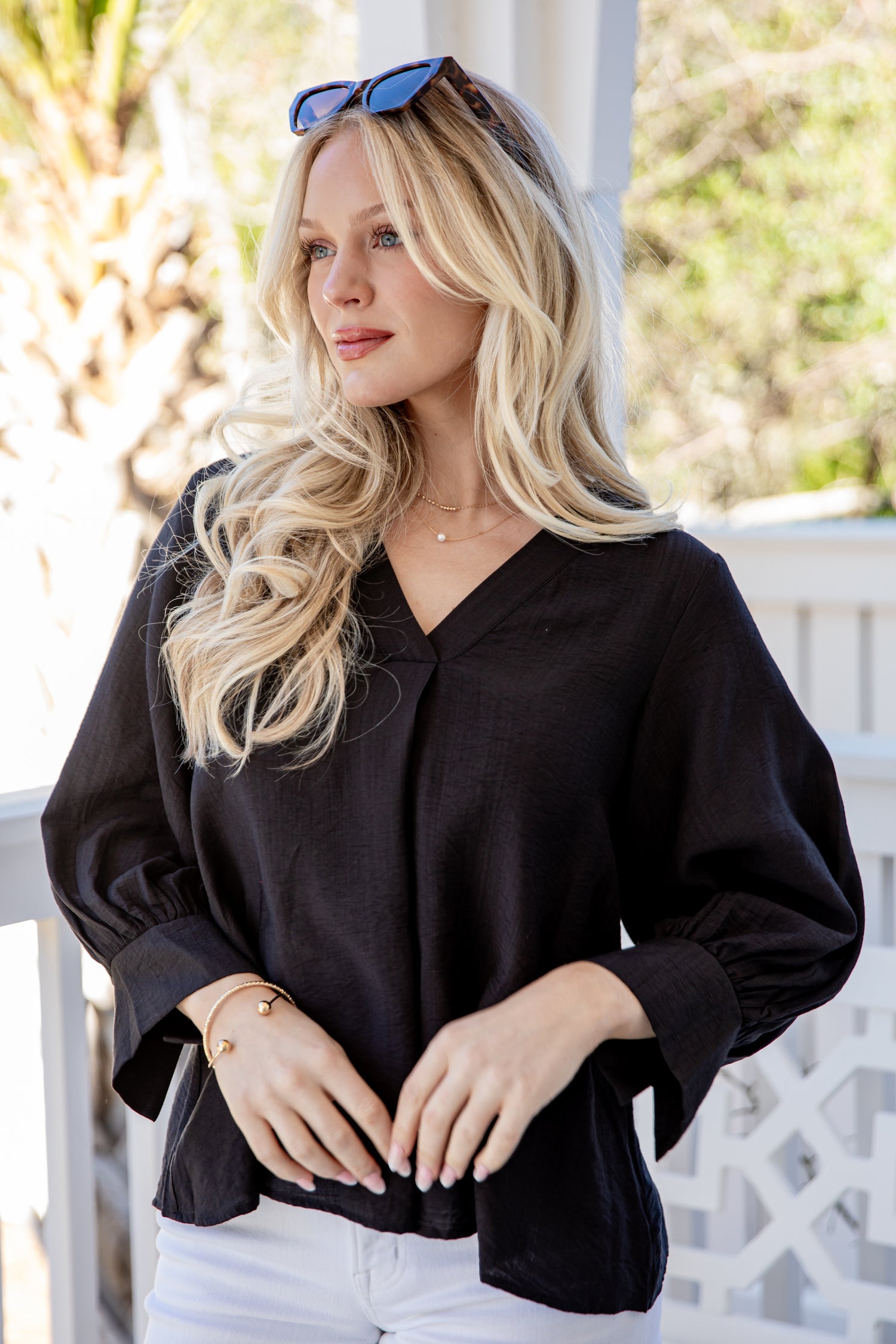 Woman wearing a black blouse with a blurred outdoor background