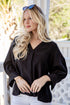 Woman wearing a black blouse with a blurred outdoor background