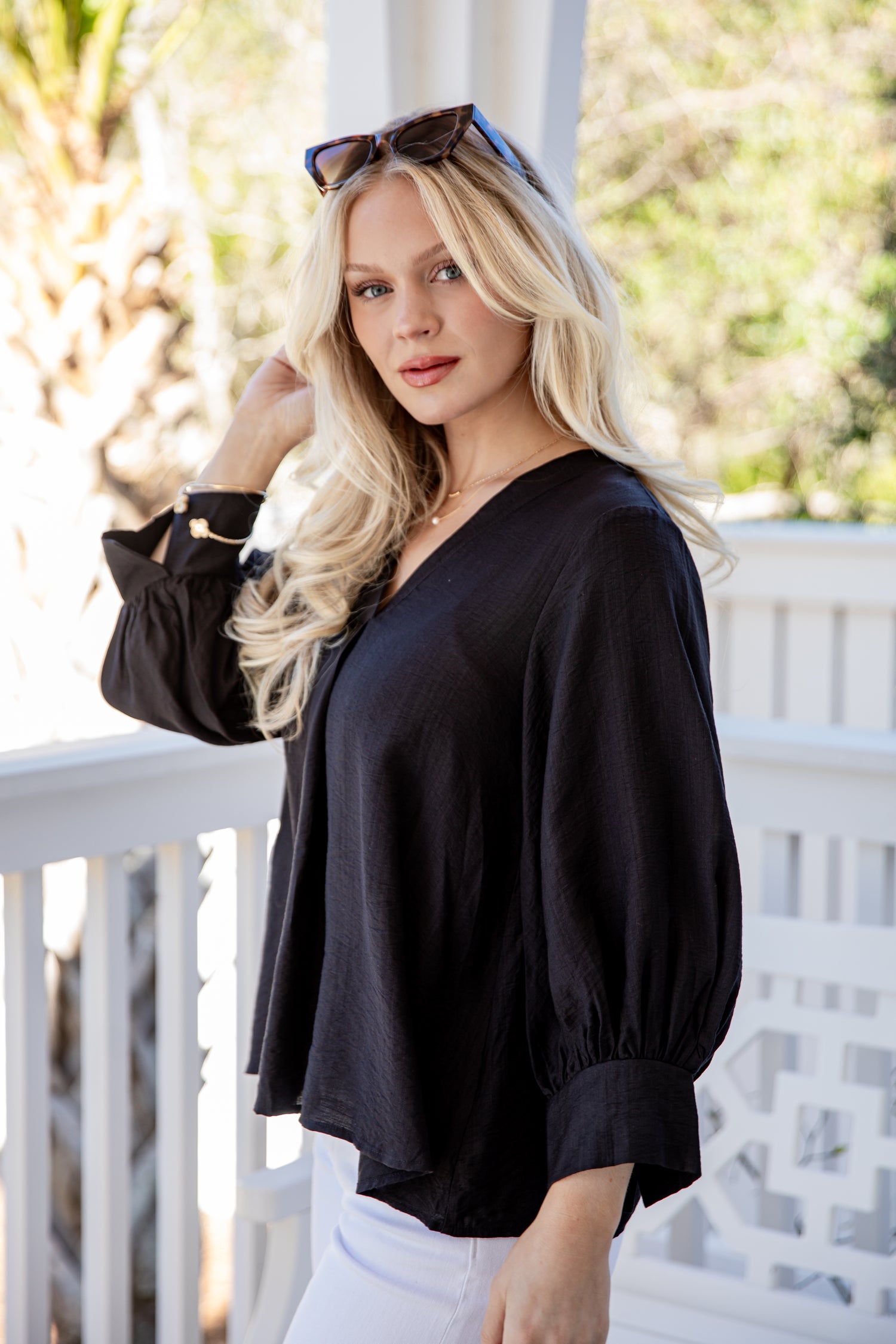 Woman wearing a black blouse and white pants on a balcony