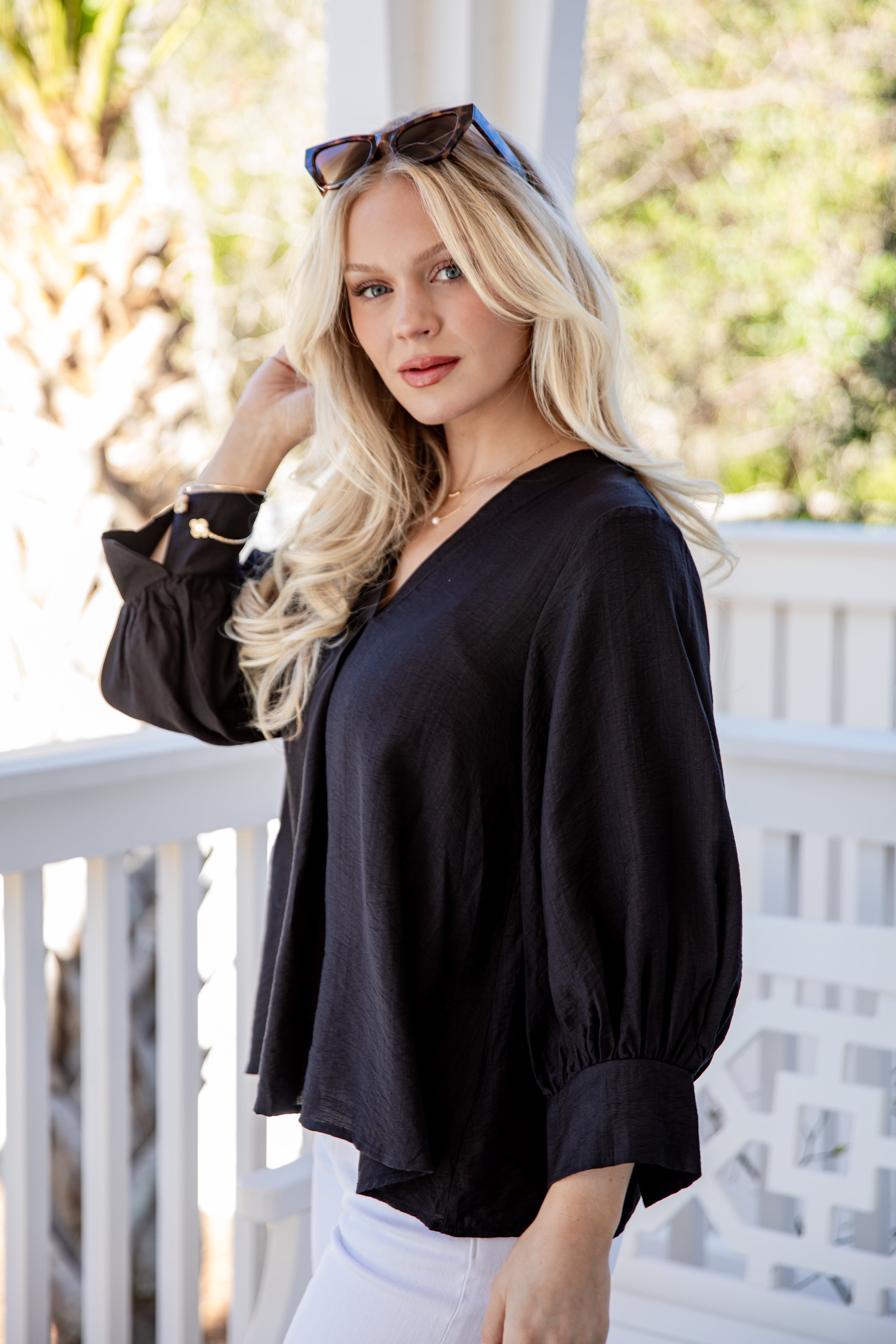 Woman wearing a black blouse and white pants on a balcony
