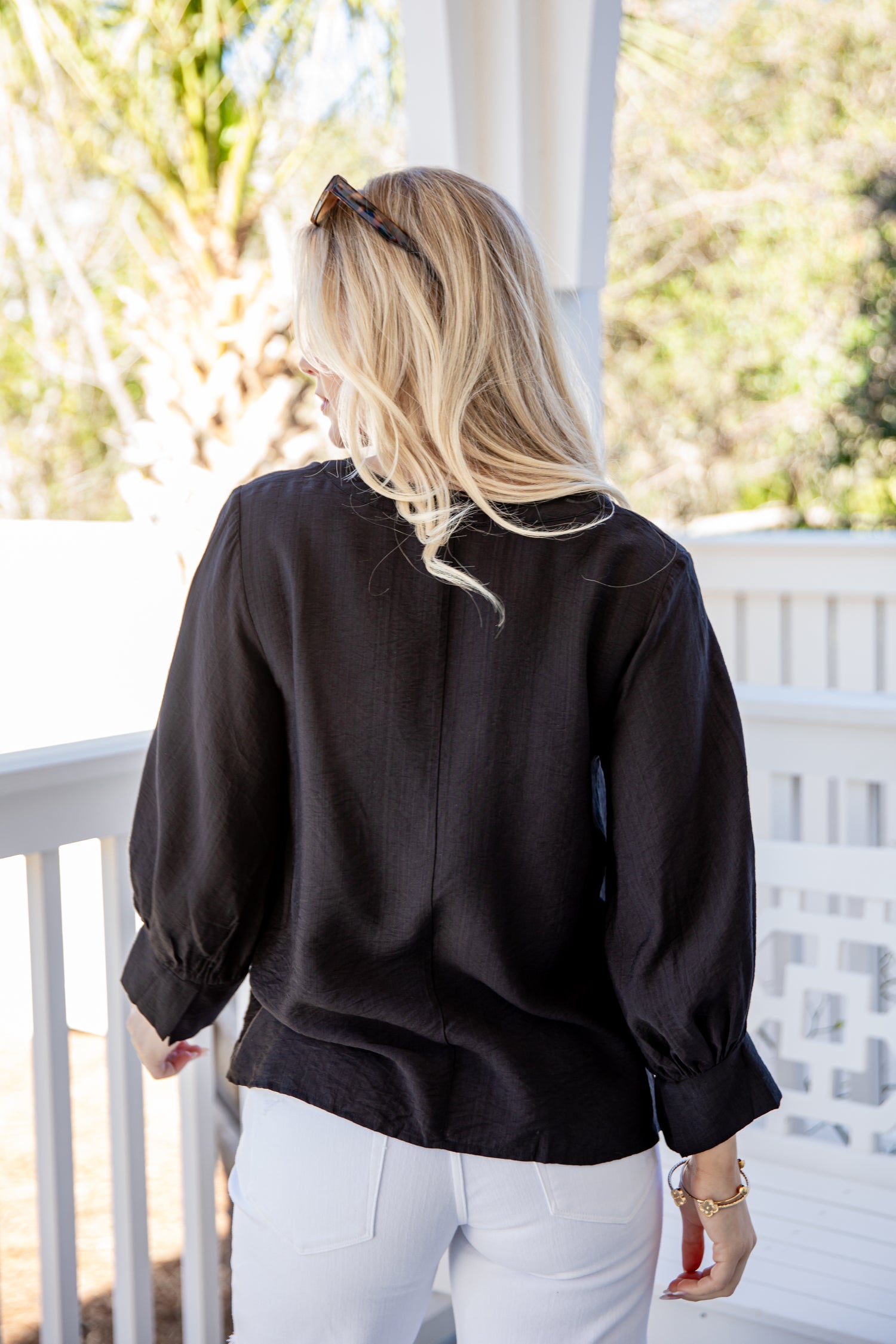 Woman wearing a black blouse and white pants on a balcony