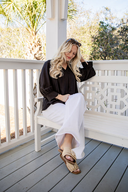 Woman sitting on a white bench on a wooden deck with trees in the background