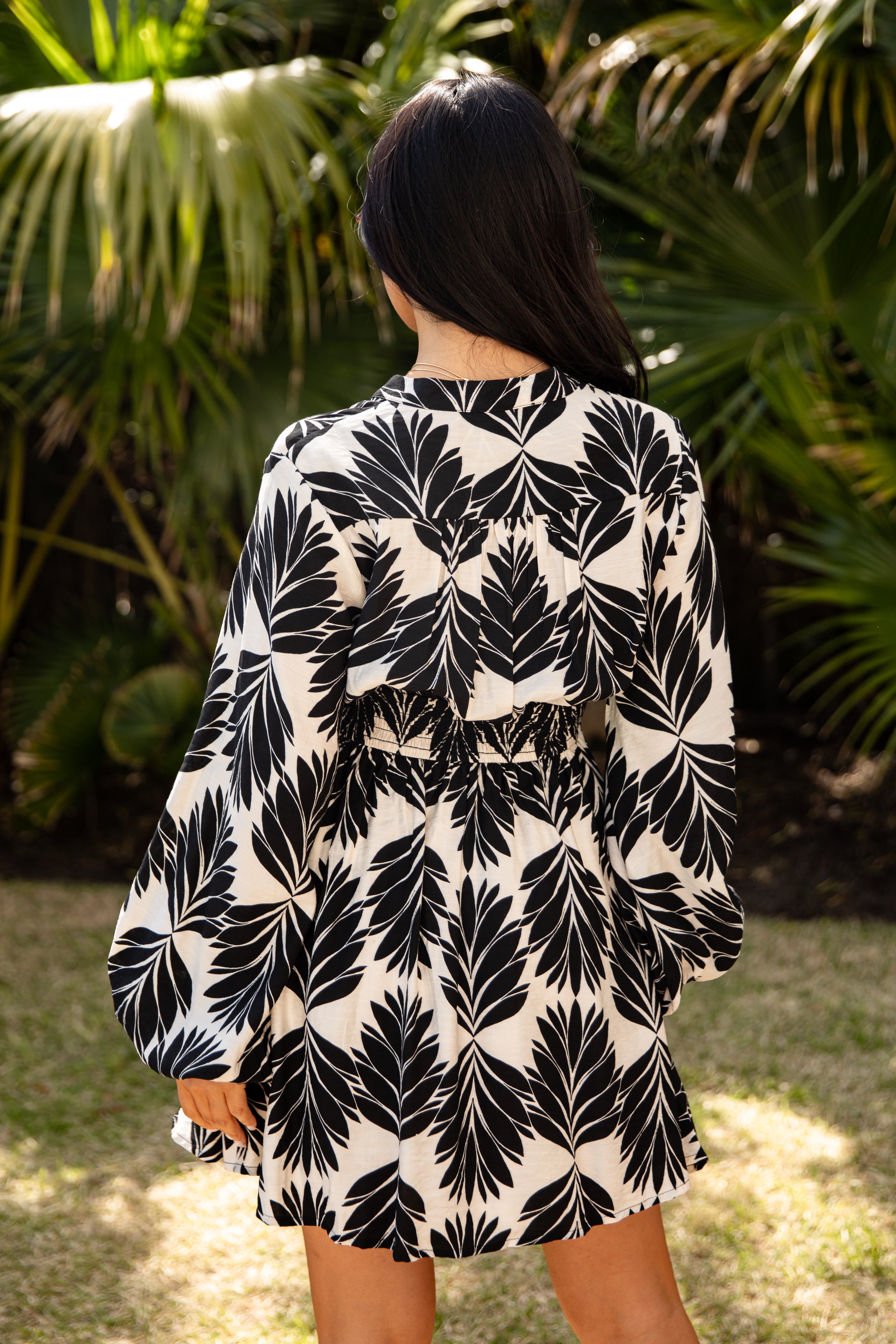 Person wearing a black and white leaf pattern dress in a garden setting