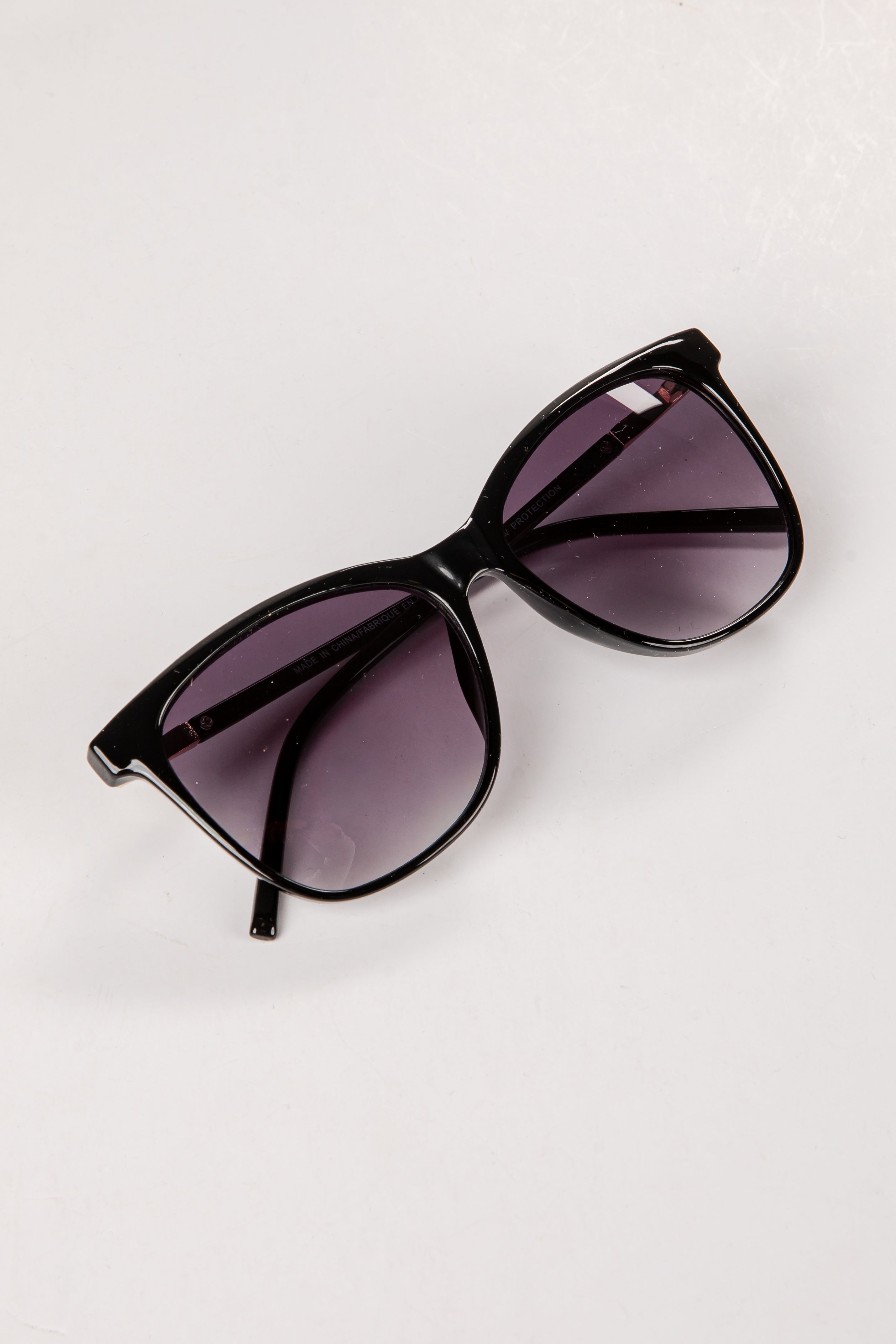 Black sunglasses with purple lenses on a white background