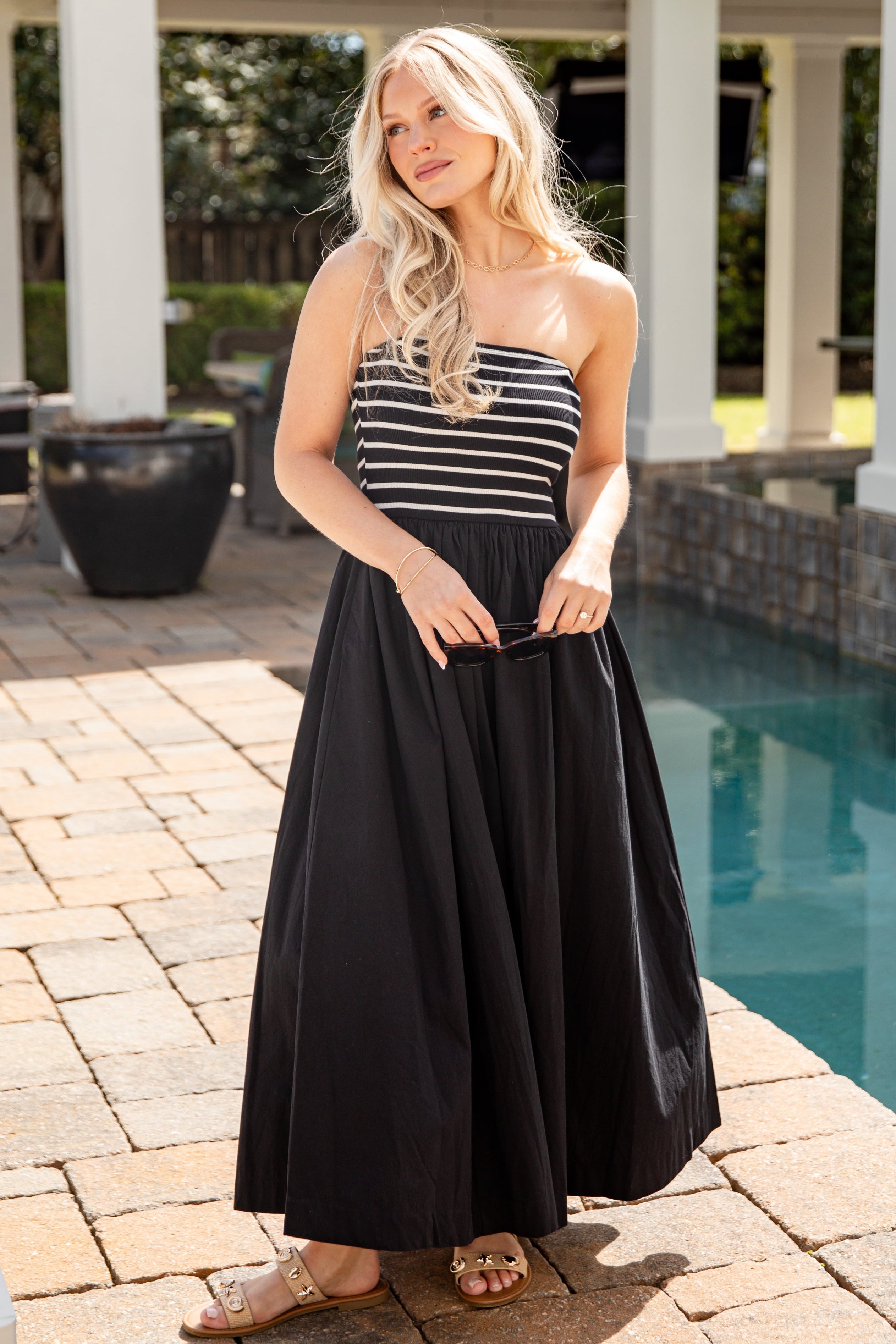 Woman in a black and white striped dress standing by a pool