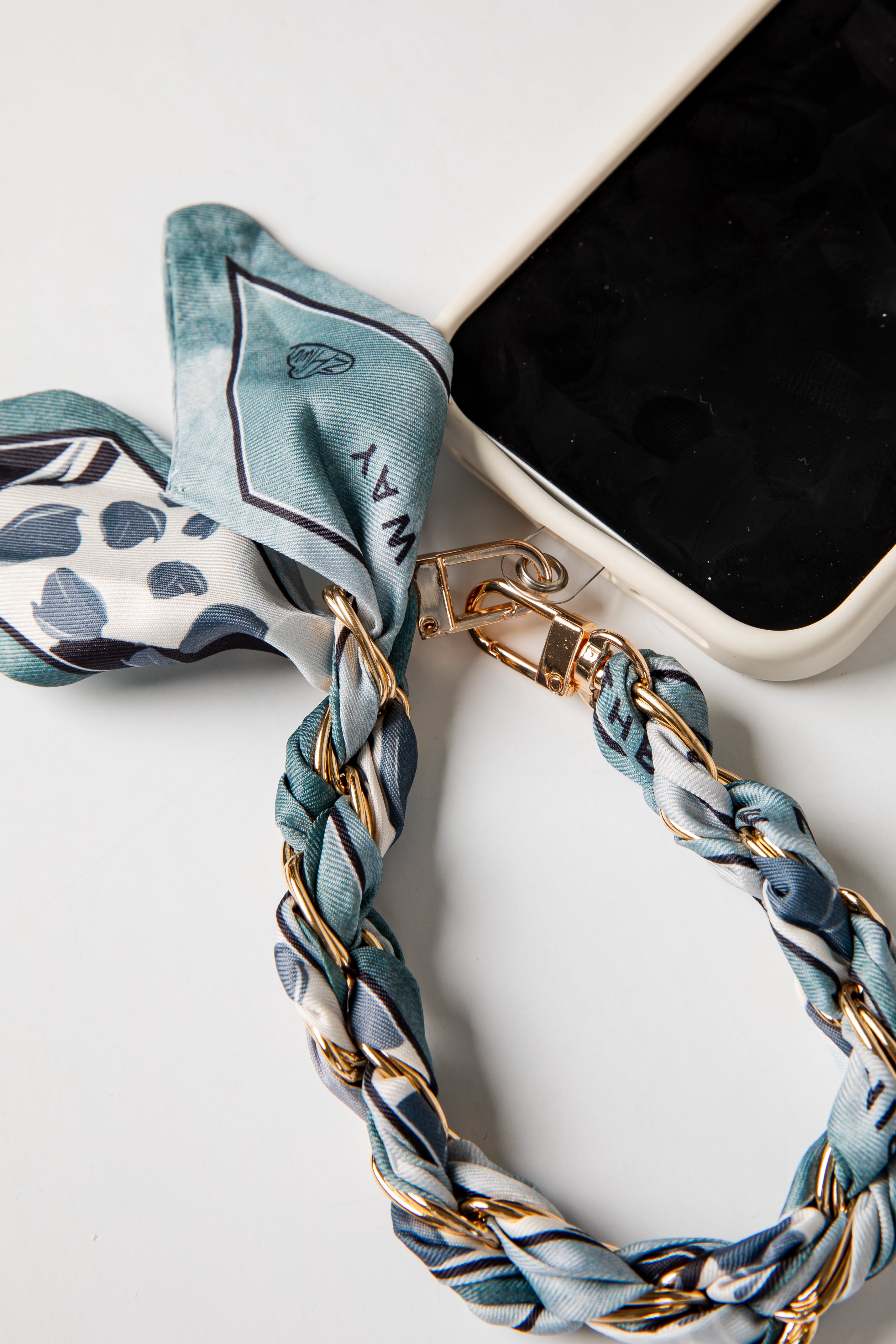 Phone case with a blue and white striped scarf accessory on a white background