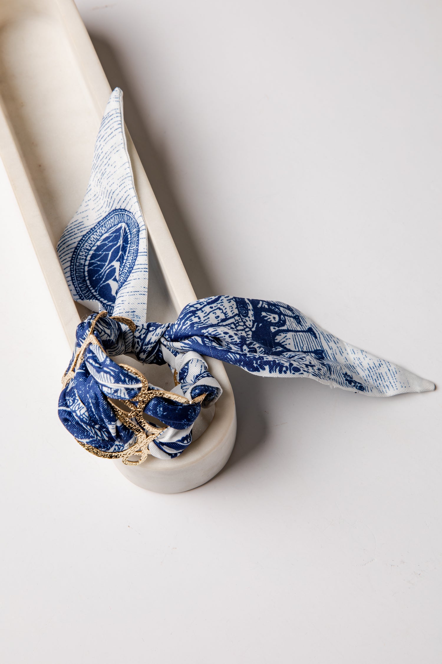 White ceramic with a blue and white patterned cloth tied around it on a light gray background